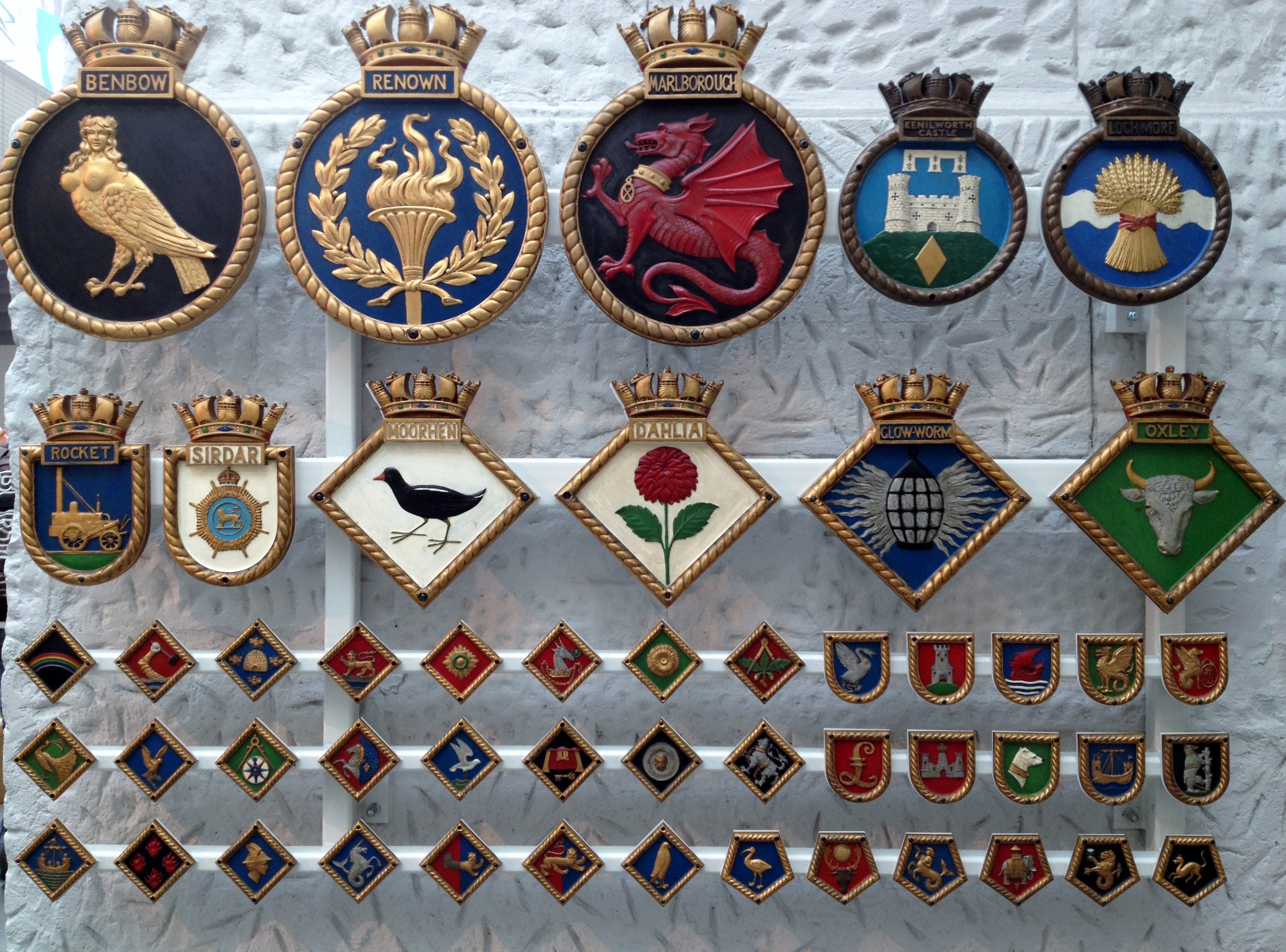 Ship badges from the National Maritime Museum. The top row shows HMS Benbow, HMS Renown, HMS Marlborough, HMS Kenilworth Castle and HMS Loch More